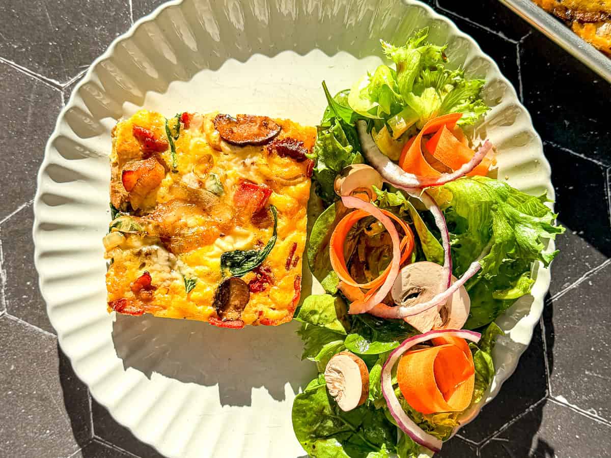 Frittata with a side salad on a tan scalloped plate.