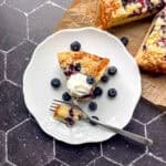 White plate with a slice of French yogurt cake with blueberries.