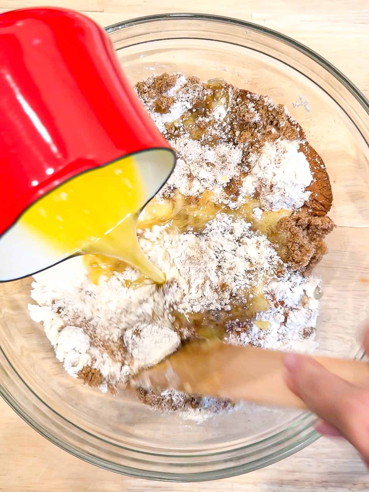Adding melted butter to dry ingredients to make crumb topping in a glass bowl.