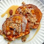 Two slices of French toast with maple syrup and granola.
