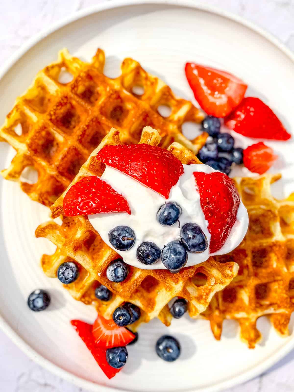 Cornmeal waffles with fresh fruit and whipped cream.