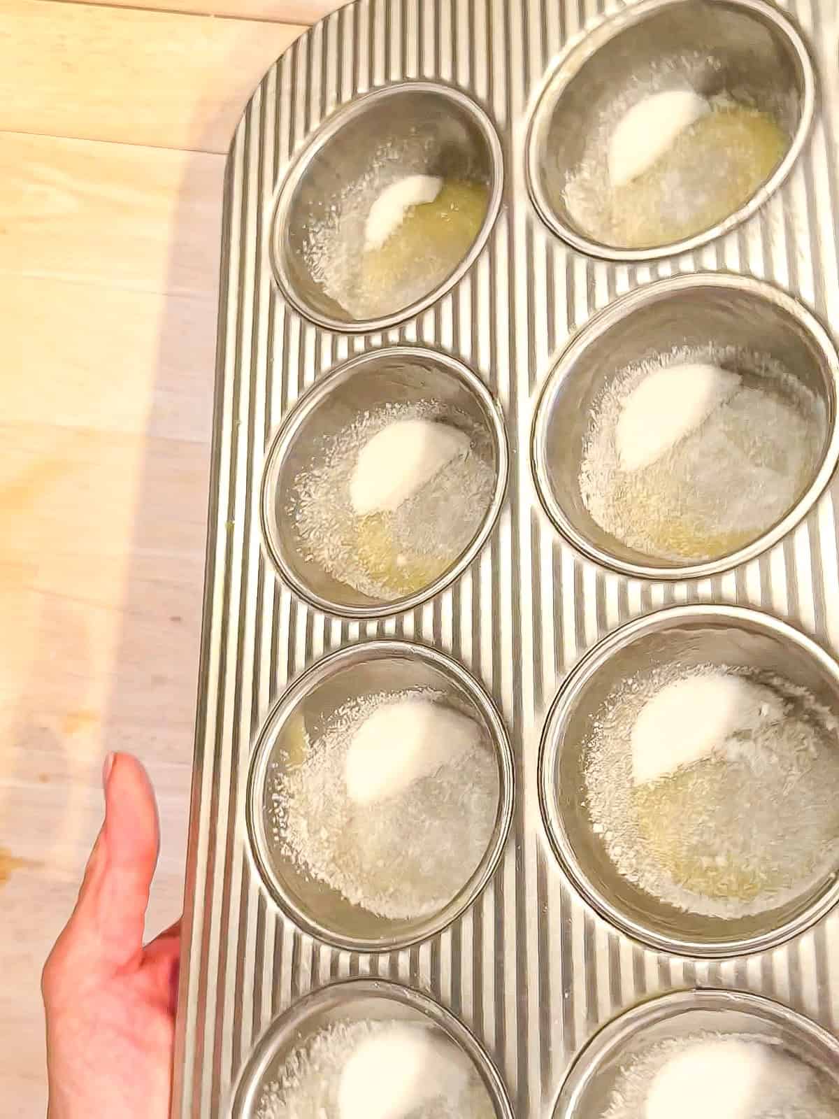 Buttering and sugaring a muffin pan.