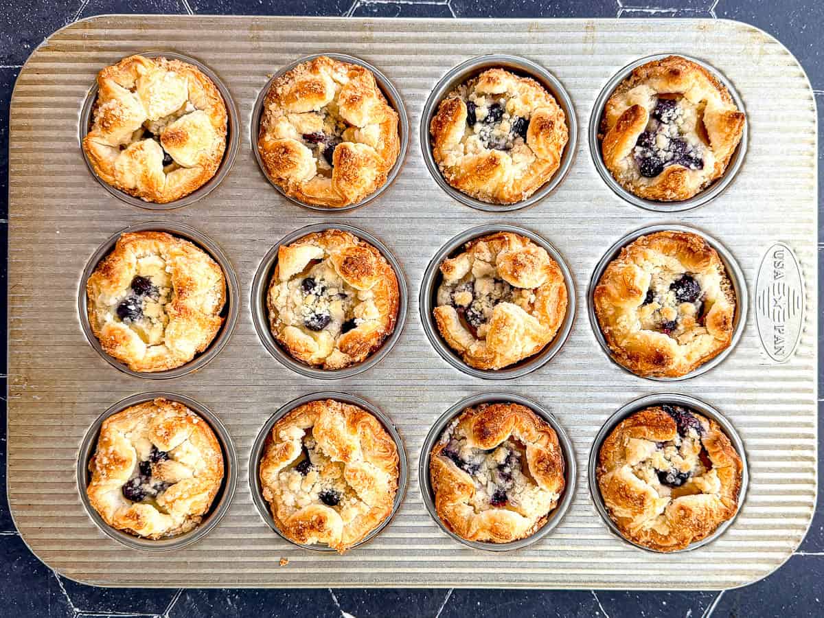 A blueberry caramelized cheesecake croissant on a white and flowered plate.