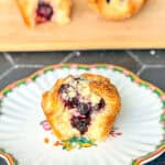 A blueberry caramelized cheesecake croissant on a white and flowered plate.