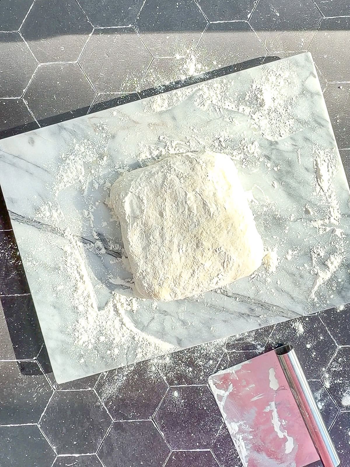 A square of ciabatta dough on a marble works surface.