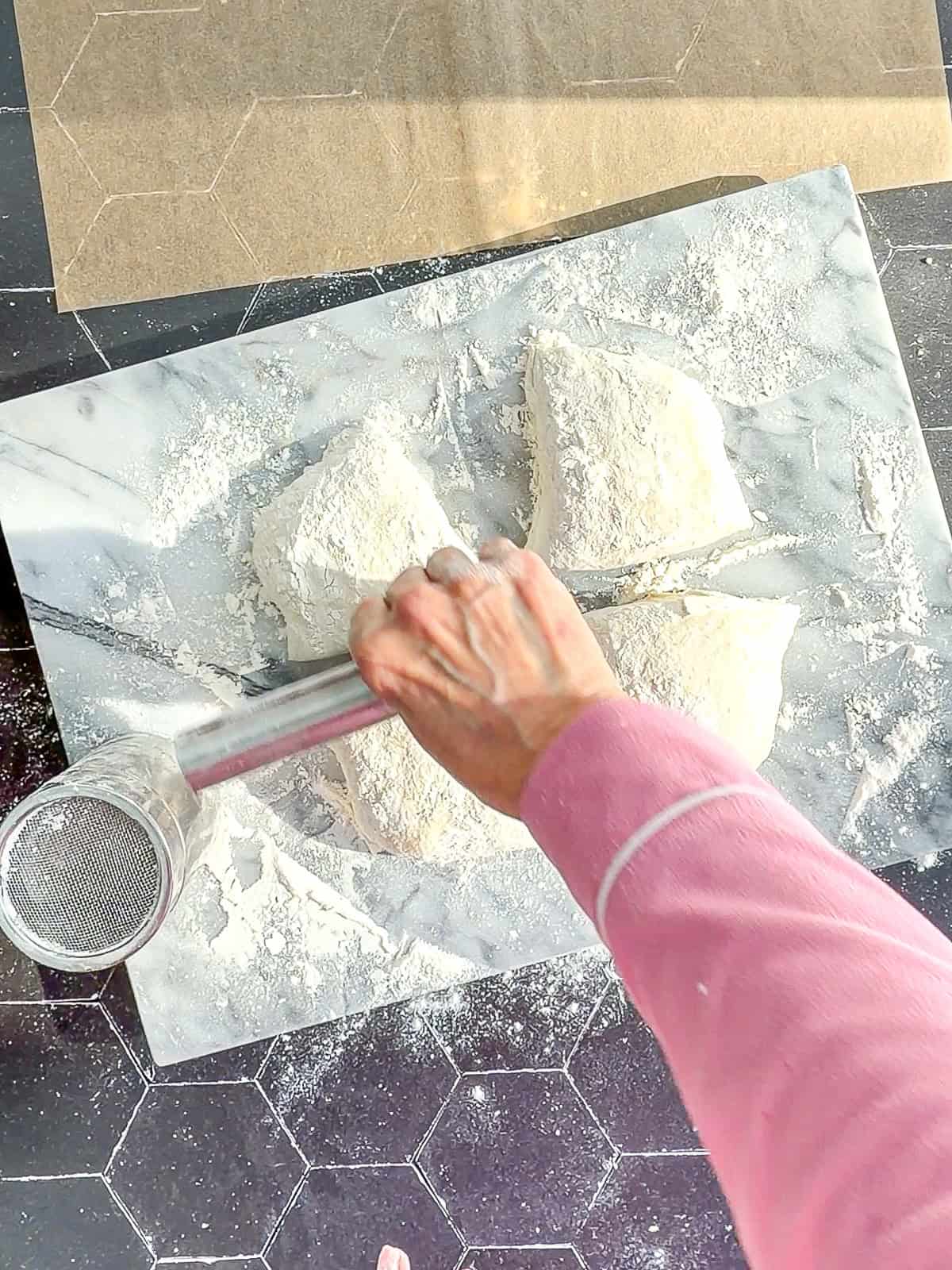 Using a bench scraper to cut ciabatta dough into four pieces.