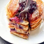 Lemon ricotta pancakes with blueberries on a white plate.