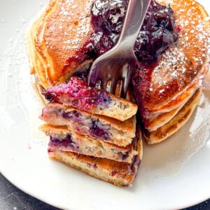 Lemon ricotta pancakes with blueberries on a white plate.