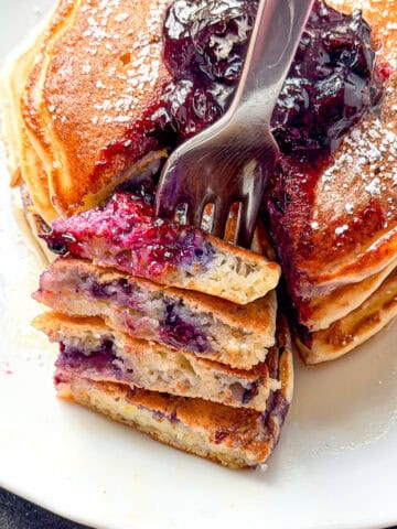 Lemon ricotta pancakes with blueberries on a white plate.
