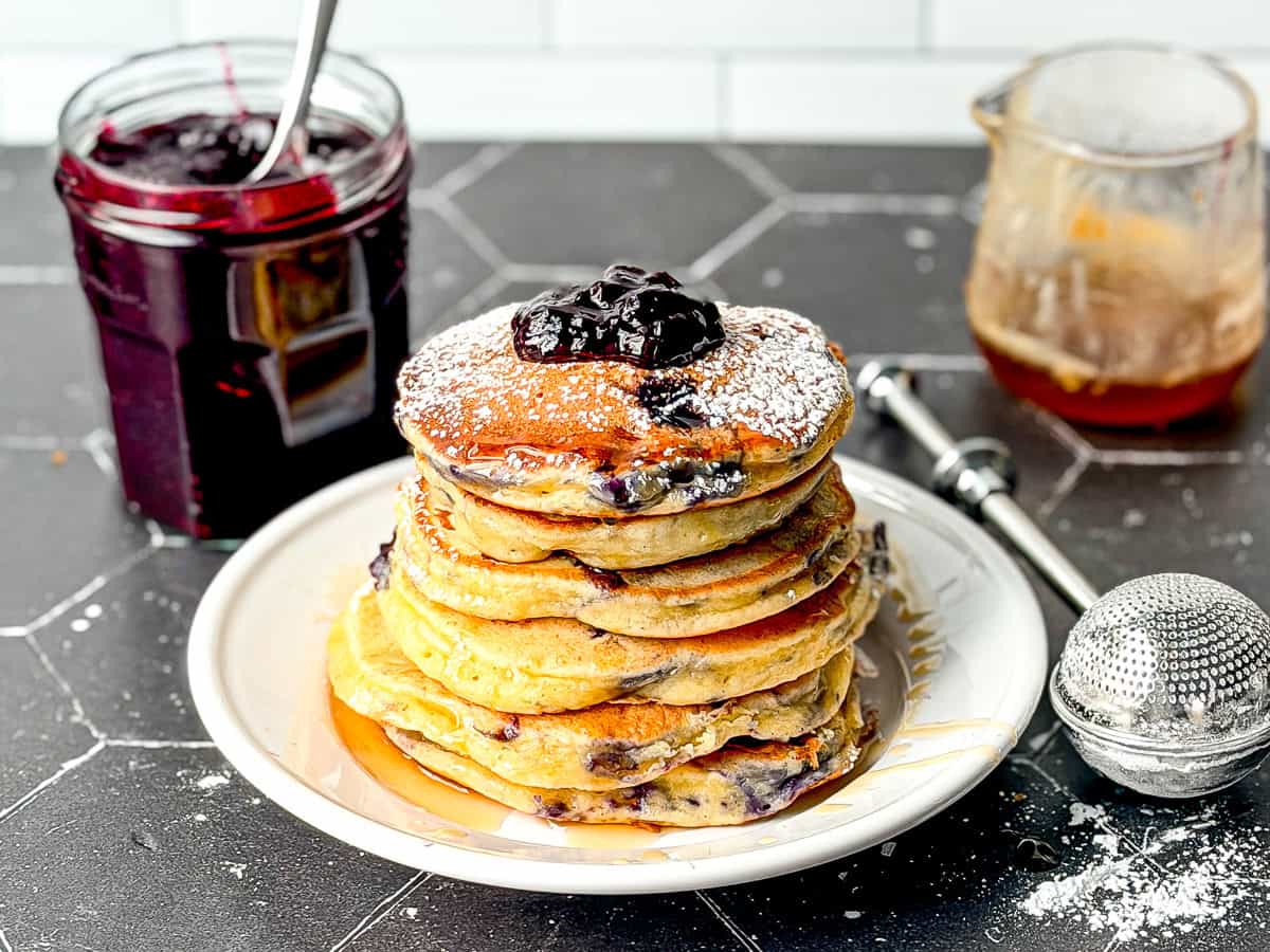 Lemon ricotta pancakes with blueberries on a white plate.