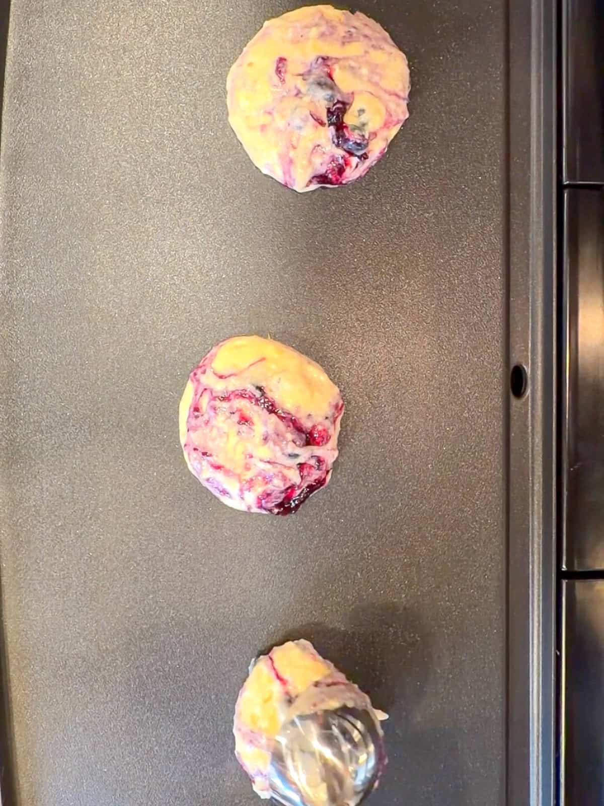 Lemon ricotta blueberries swirl pancakes on a griddle.