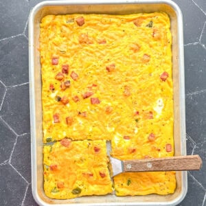 Sheet pan Denver omelette with a wooden spatula.