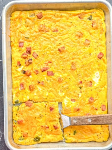 Sheet pan Denver omelette with a wooden spatula.