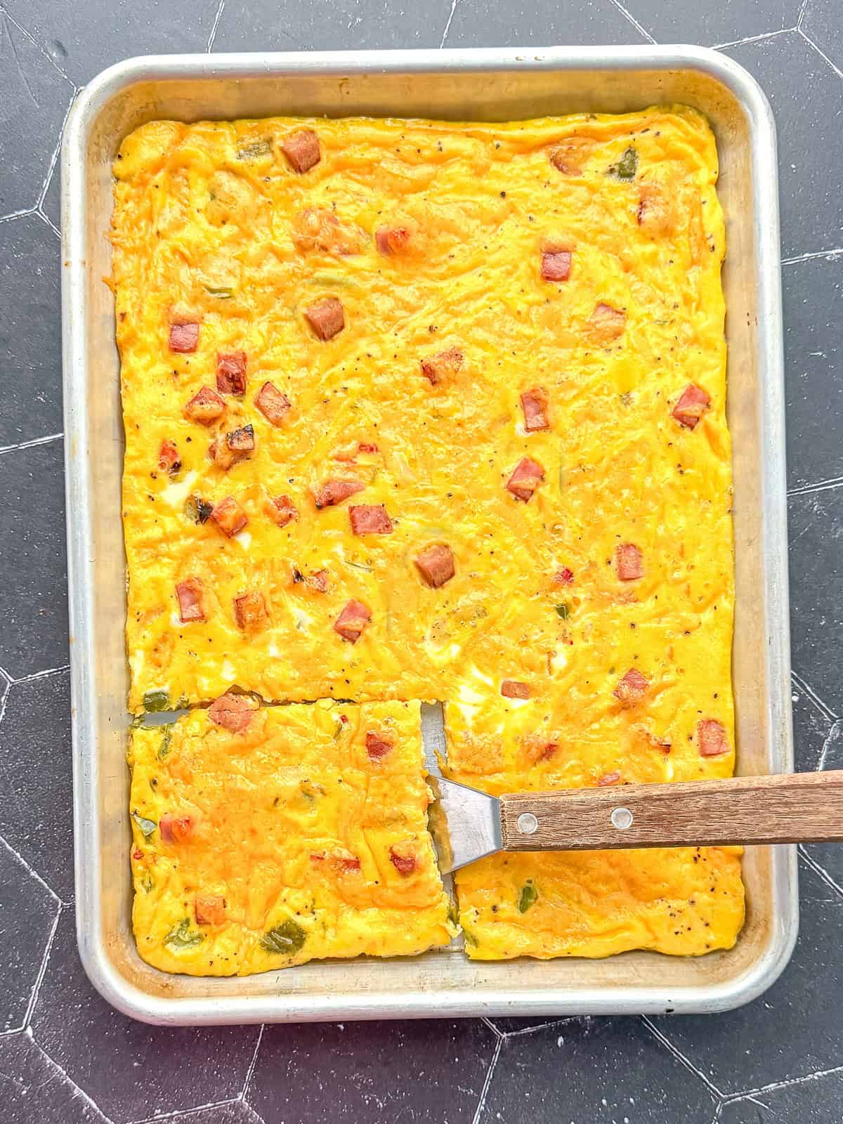 Sheet pan Denver omelette with a wooden spatula.