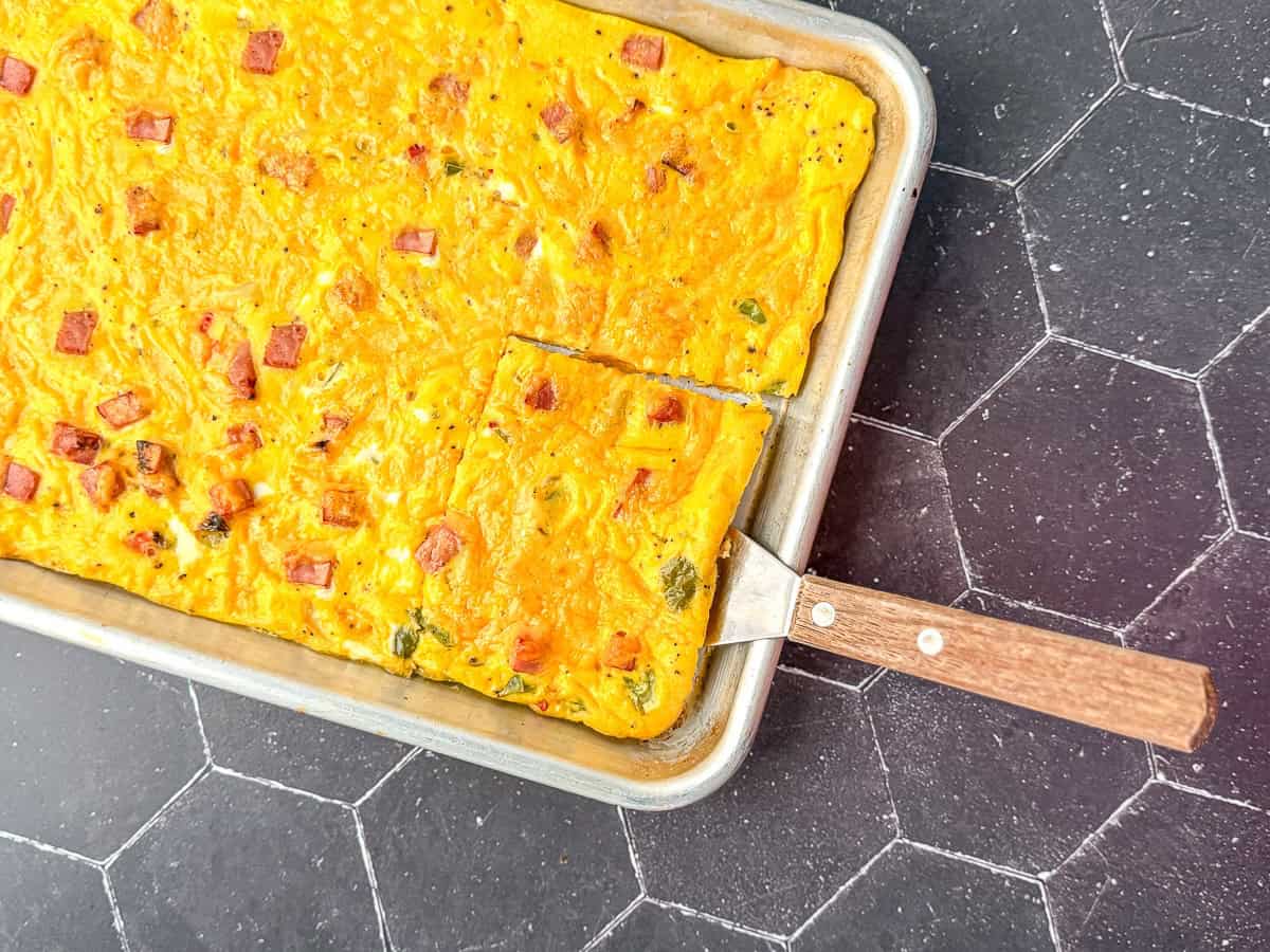 Sheet pan Denver omelette with a wooden spatula.