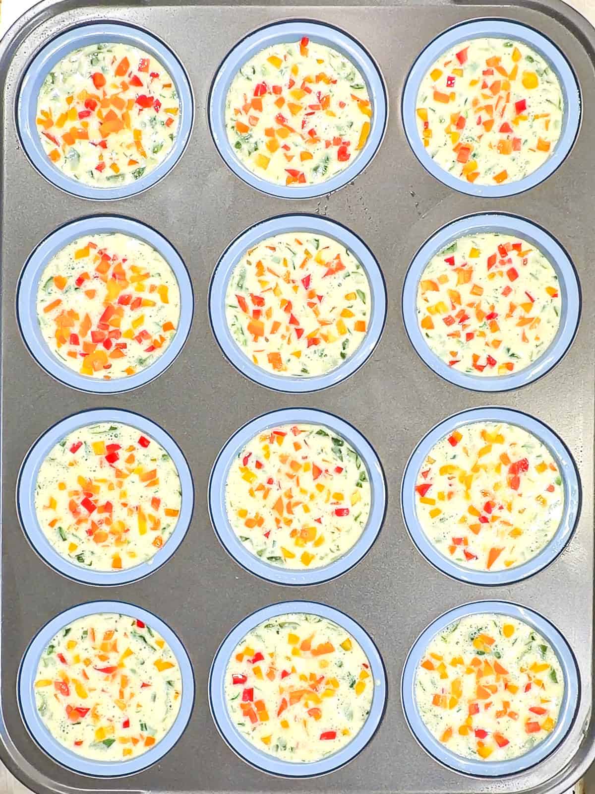 A muffin pan filled with an egg mixture.