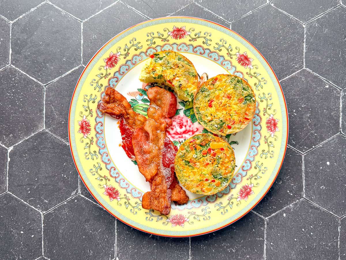 Egg bites and bacon on a yellow floral plate.