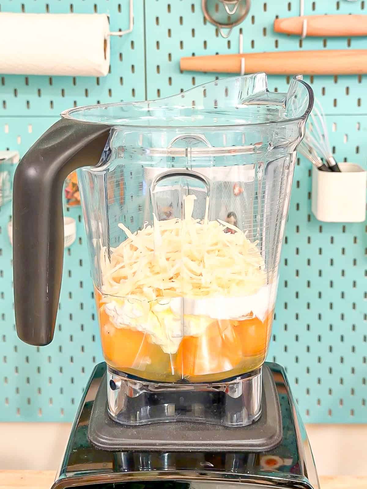 Adding eggs, cottage cheese, heavy cream, and cheese to a blender.