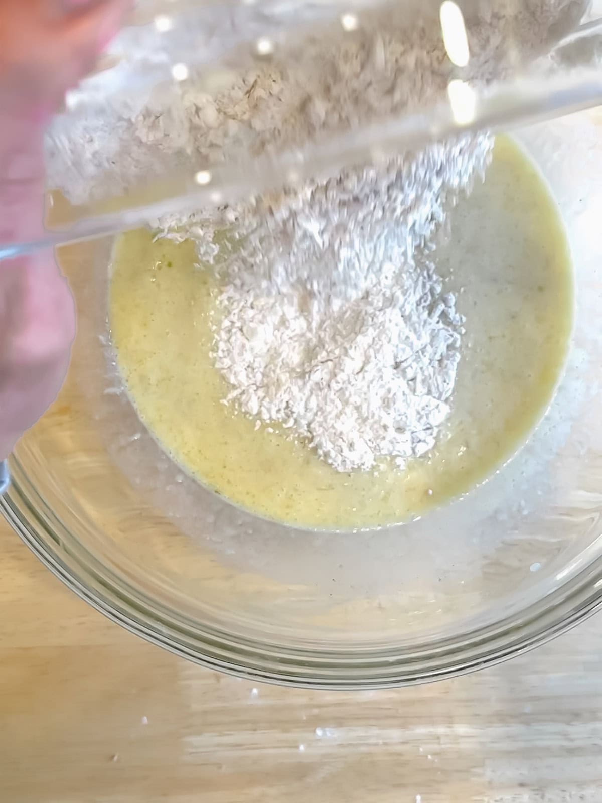 Adding dry ingredients to wet ingredients to make banana waffles.