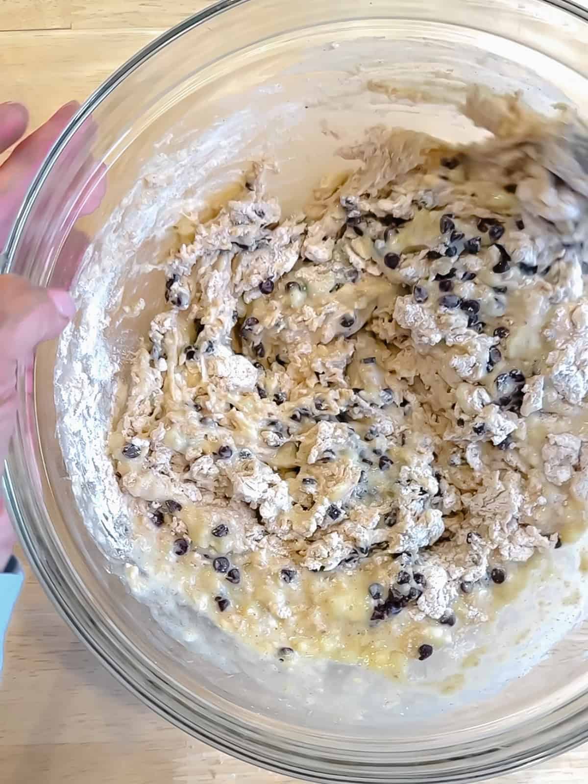 Mixing chocolate chips into banana waffle batter.