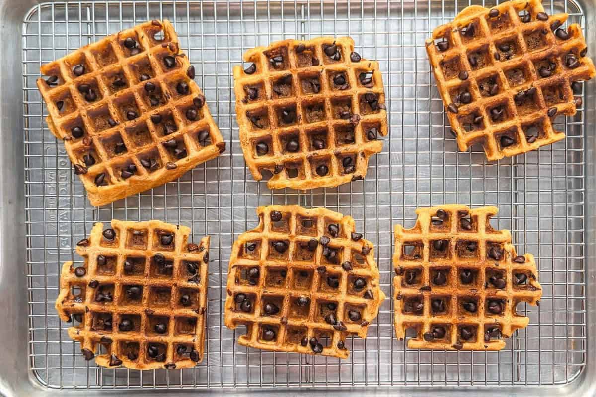Banana waffles with chocolate chips on a wire rack.