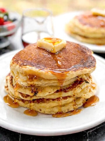 Pancakes with butter and maple syrup on a white plate.