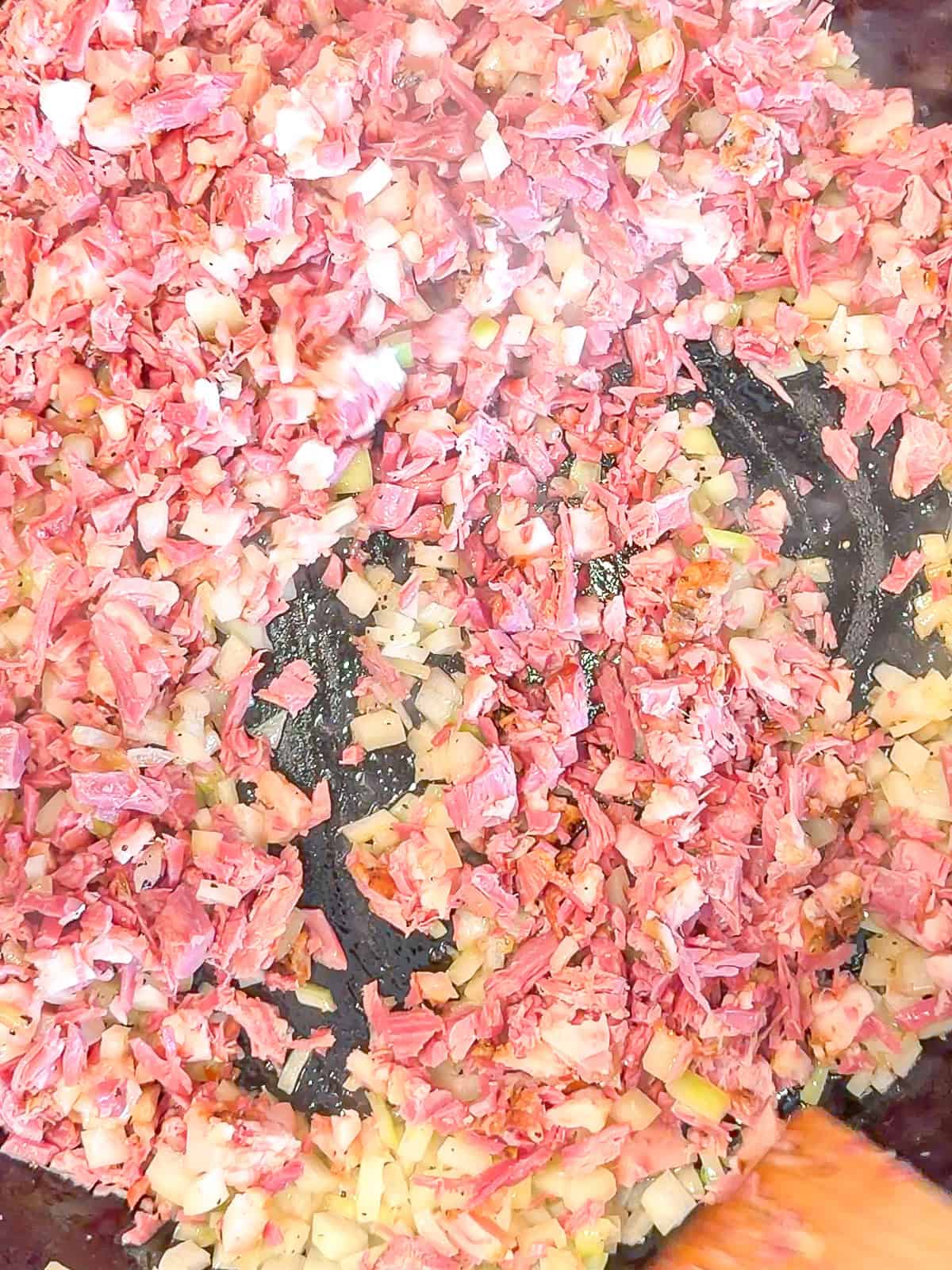 Combining chopped corned beef with sautéed onions.