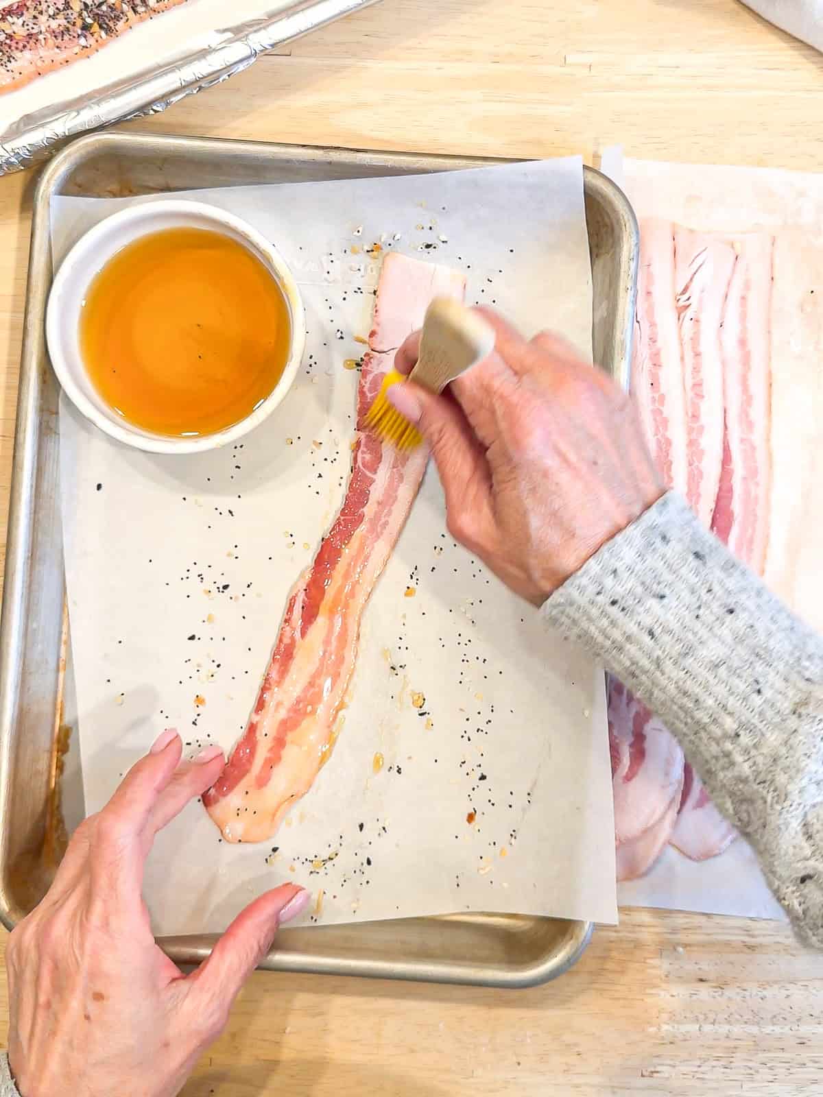 Brushing maple syrup on a strip of bacon.
