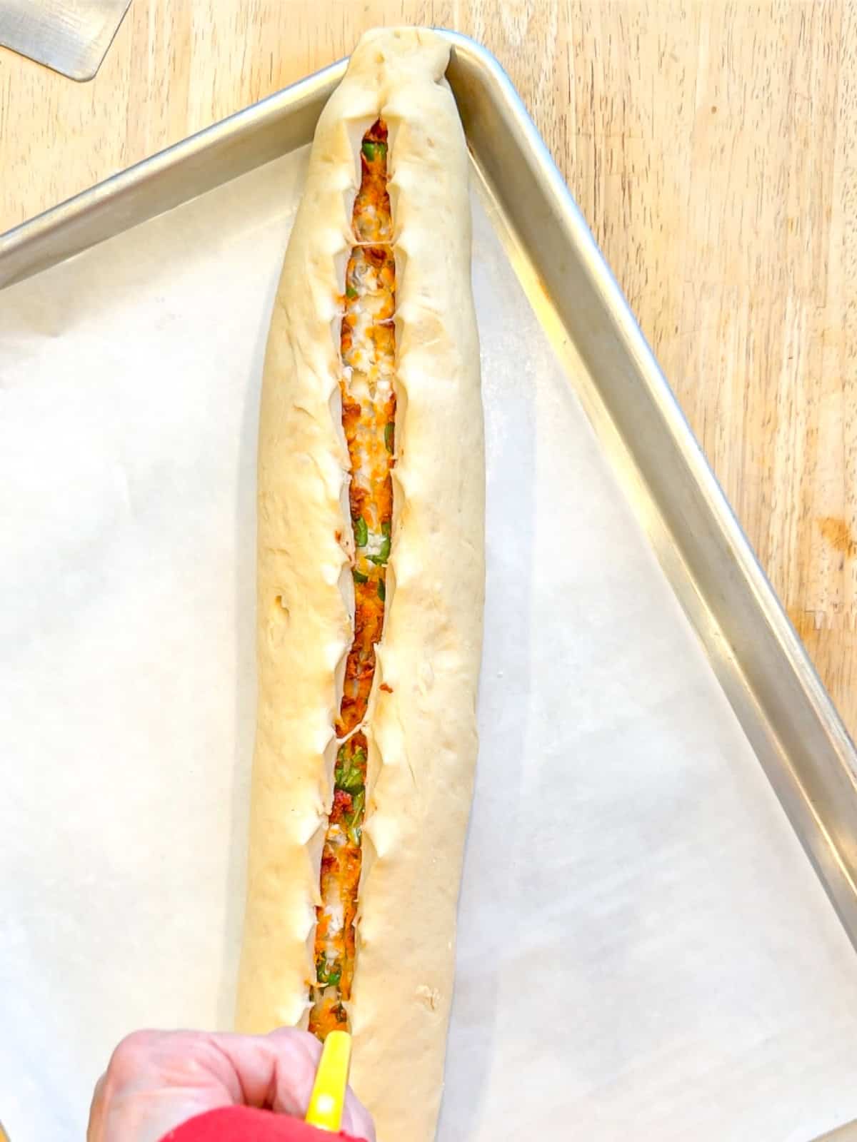 Using scissors to cut into an unbaked loaf of pane bianco.