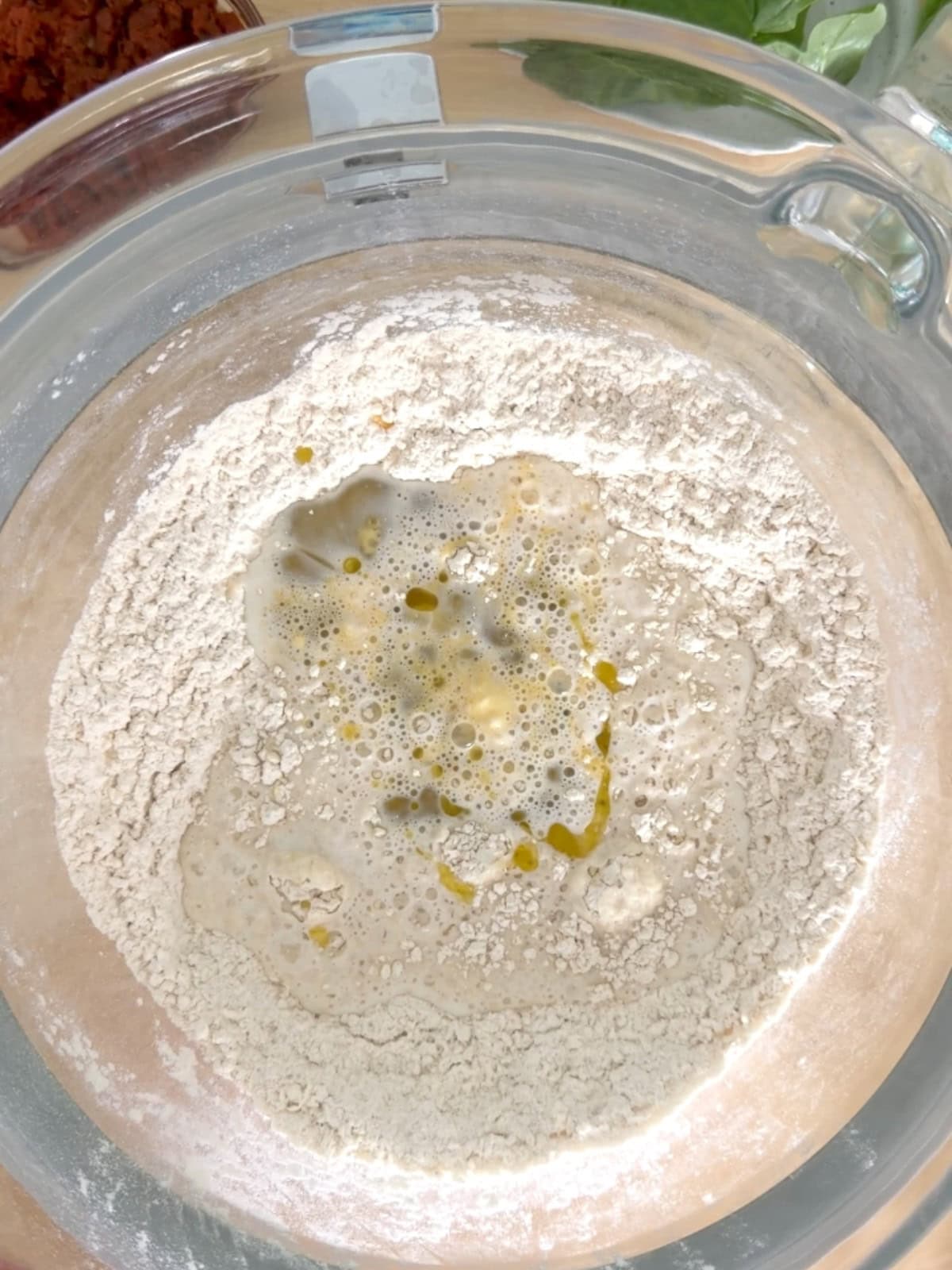 Adding milk, water, a beaten egg, and olive oil to bread dry ingredients.
