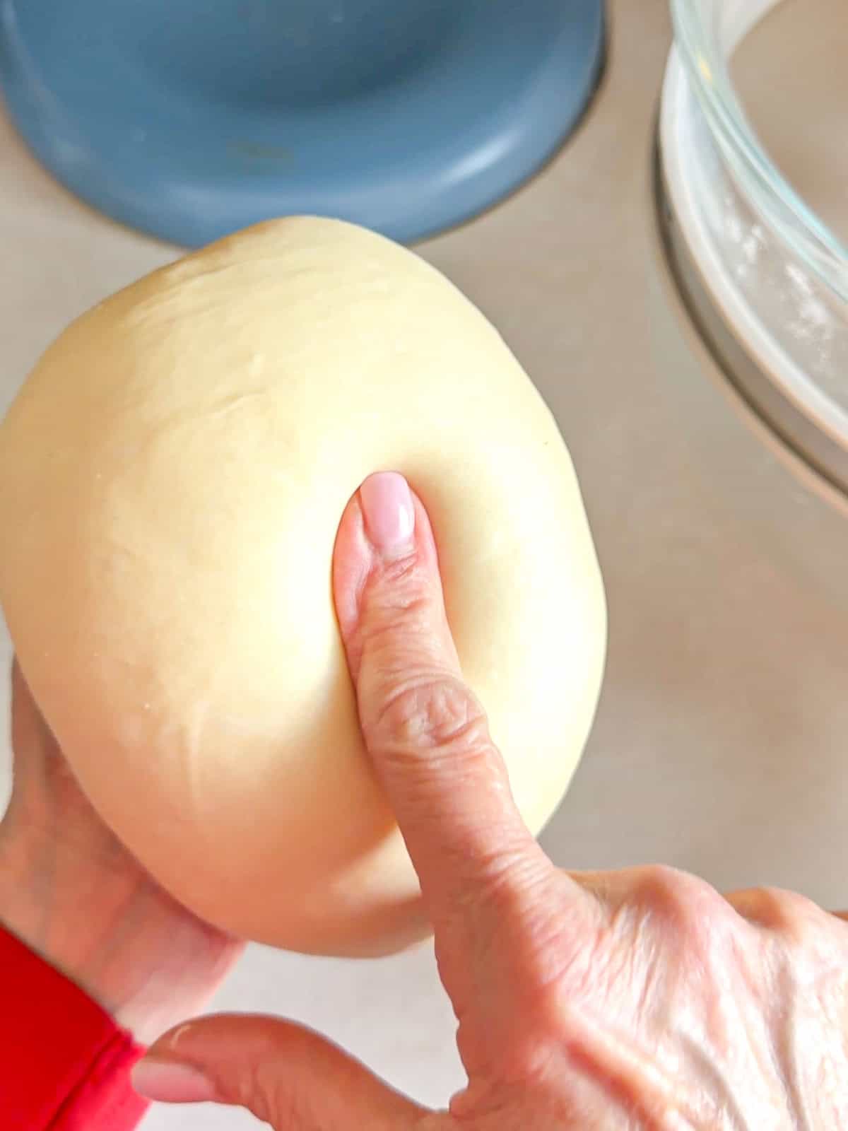 Poking a finger into a ball of dough to check its consistency.