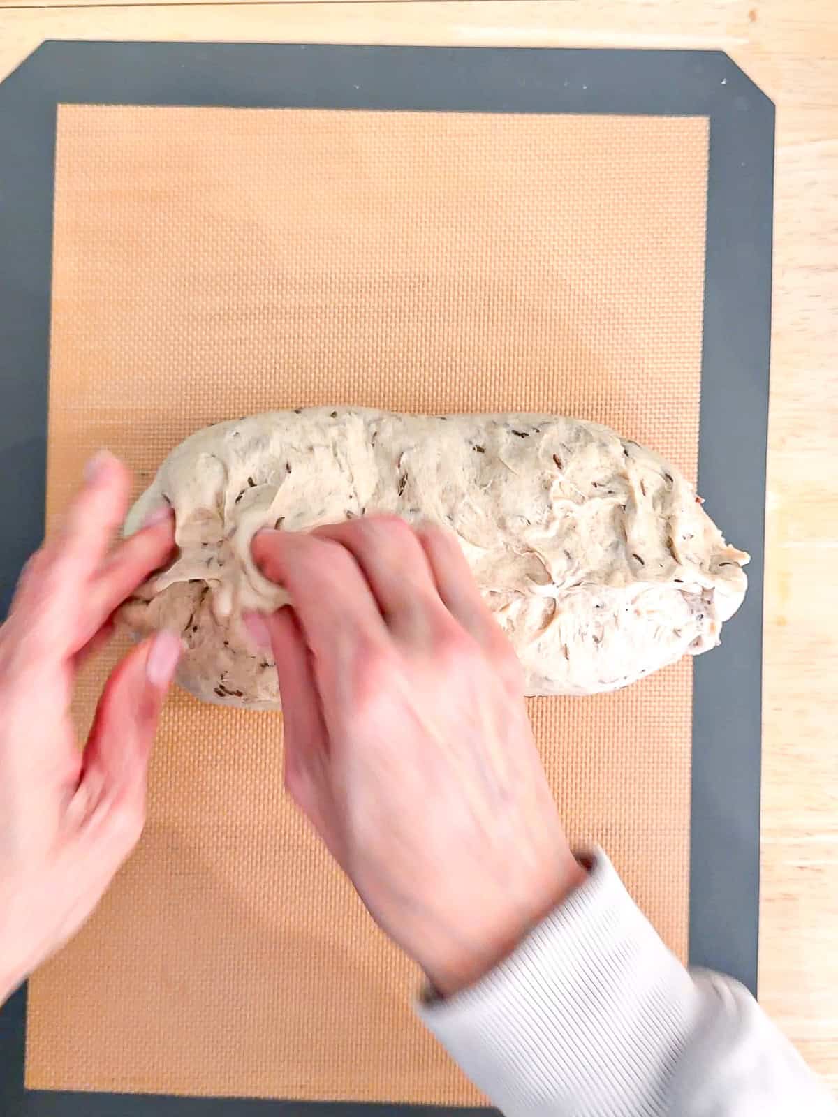Pinching the seam of a log of dough shut.