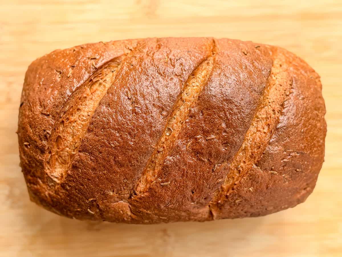 A loaf of rye bread on a wooden cutting board.