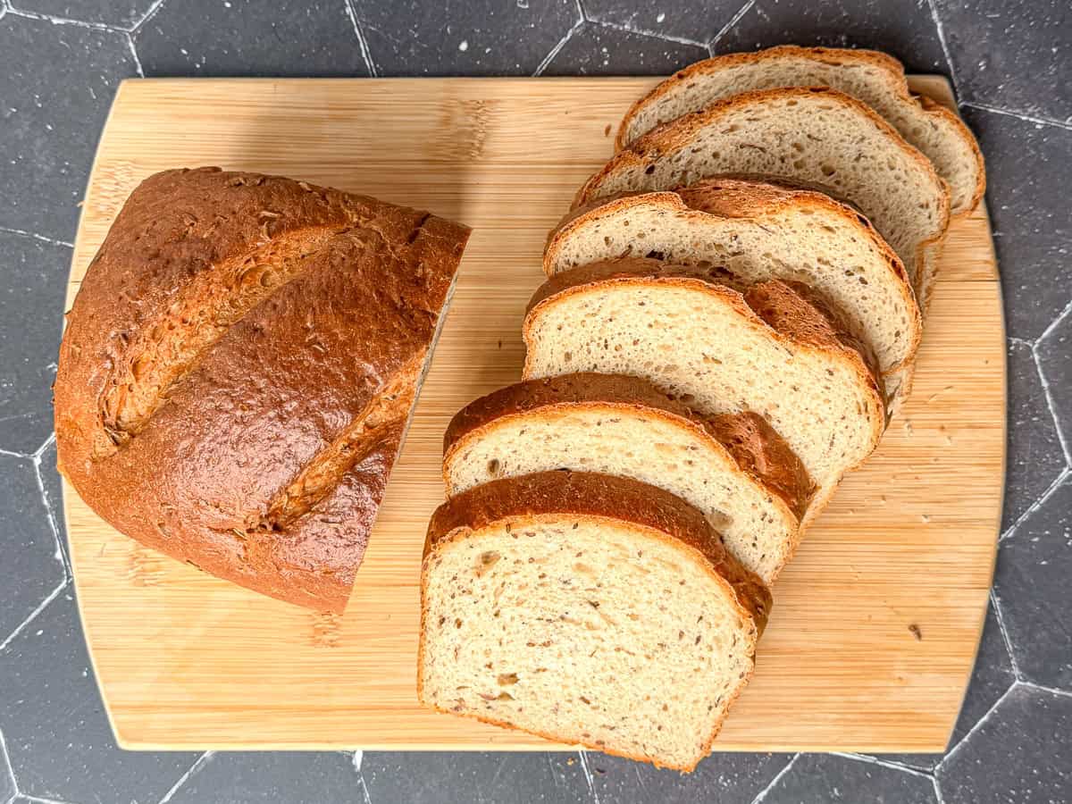 A sliced loaf of rye bread on a wooden cutting board.