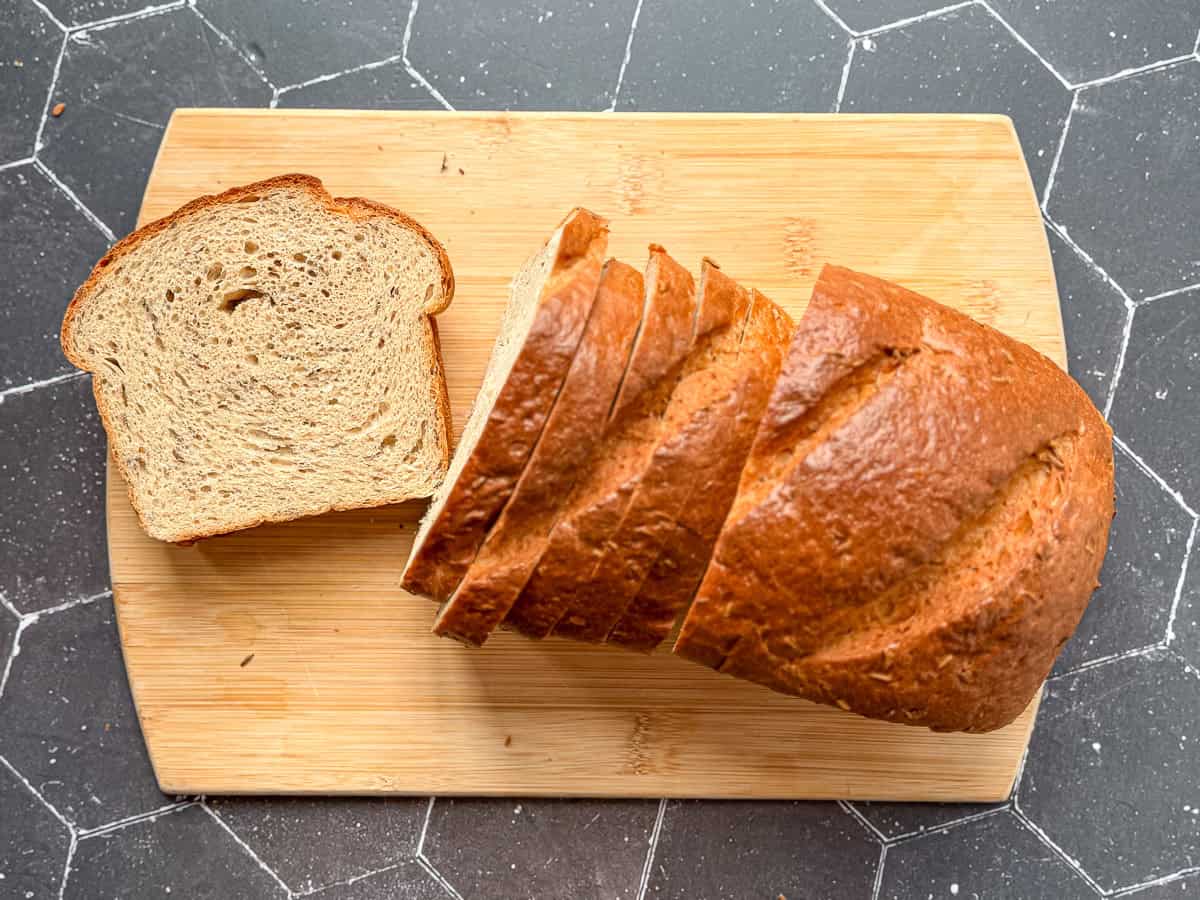 A sliced loaf of rye bread on a wooden cutting board.
