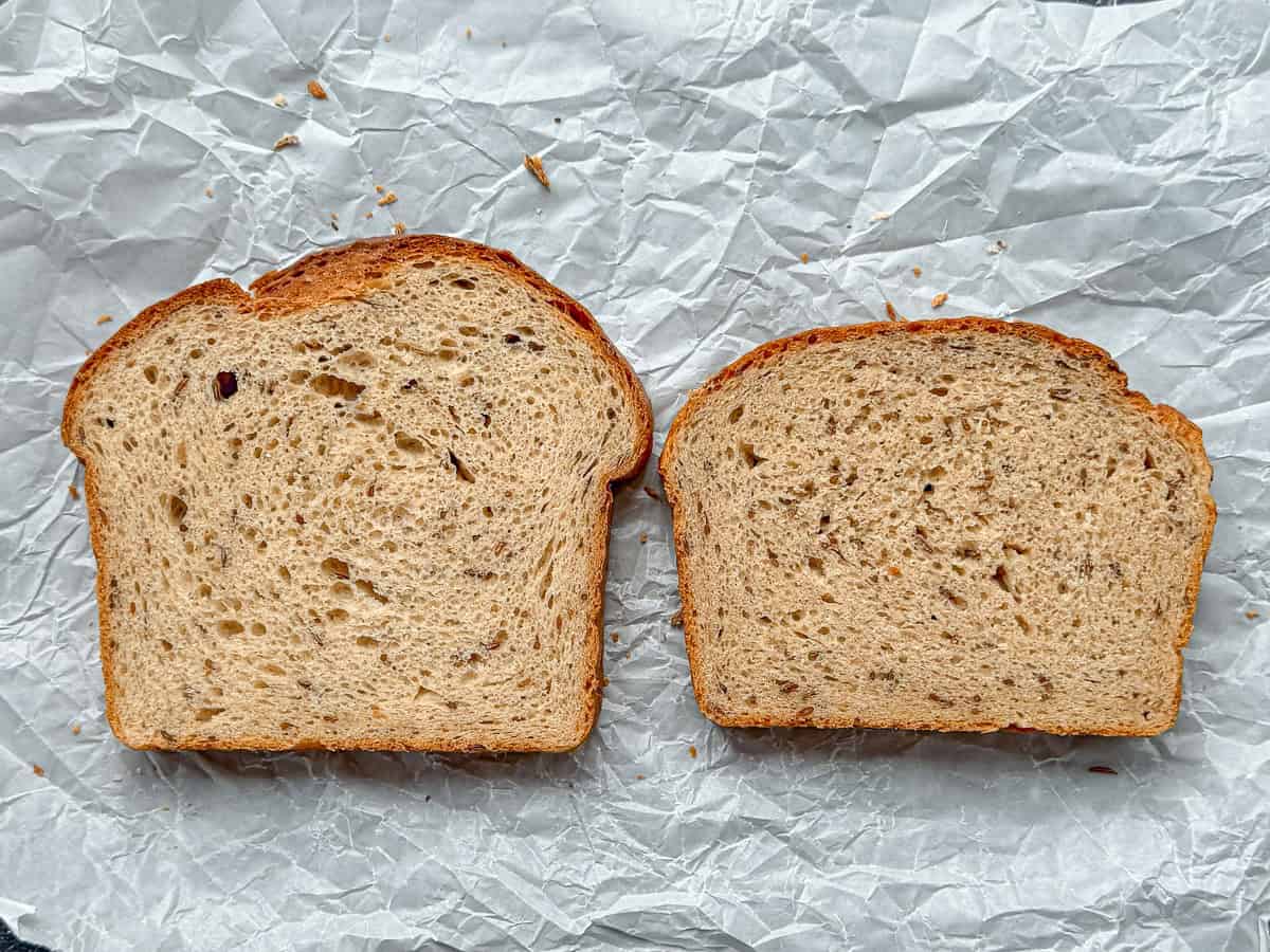 Two slices of rye bread on a piece of parchment paper.
