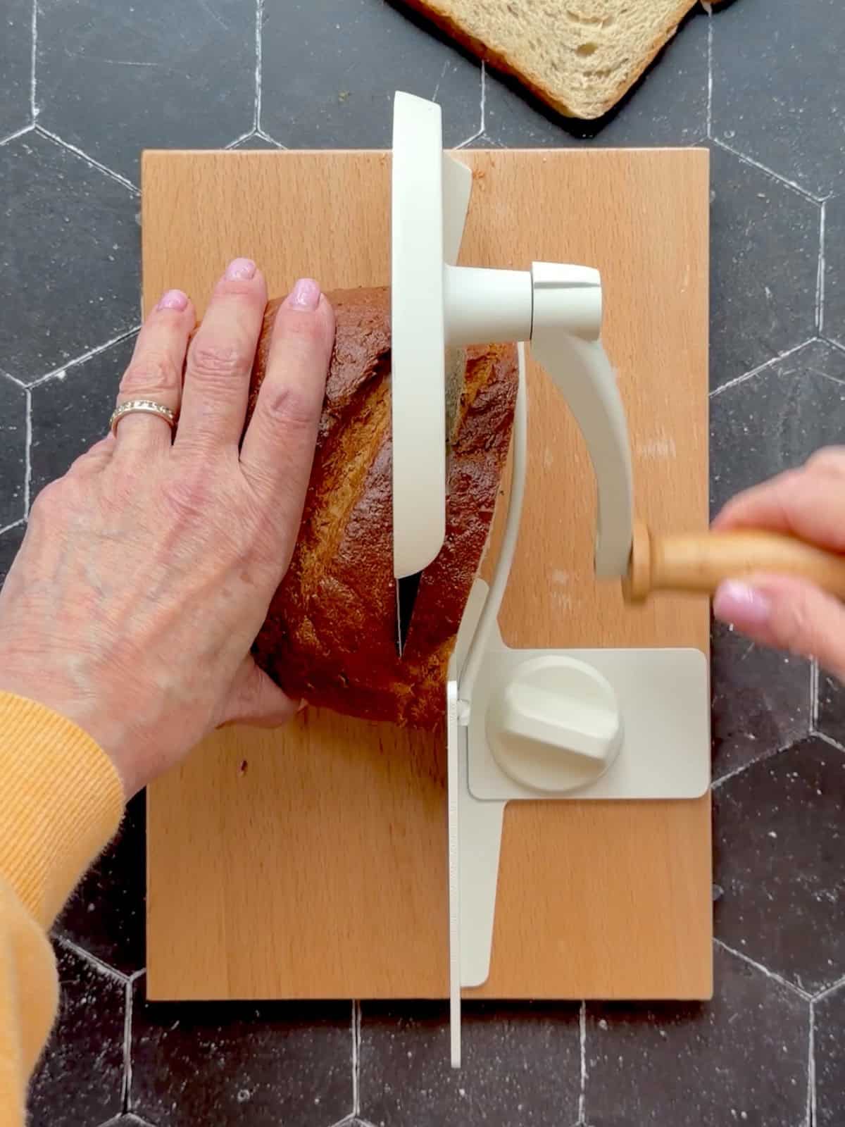 Slicing bread with a hand crank bread slicer.