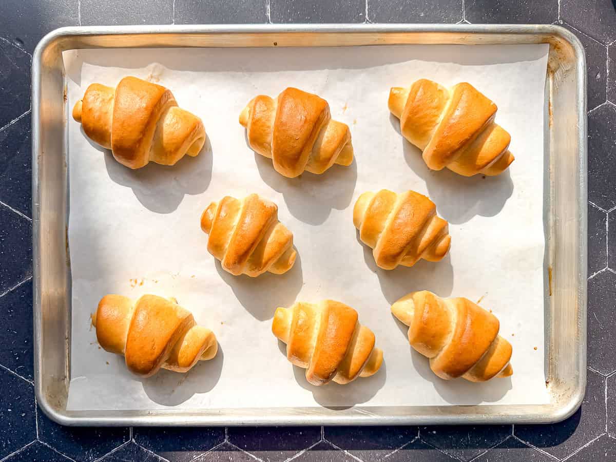Crescent rolls on a parchment paper lined sheet pan.