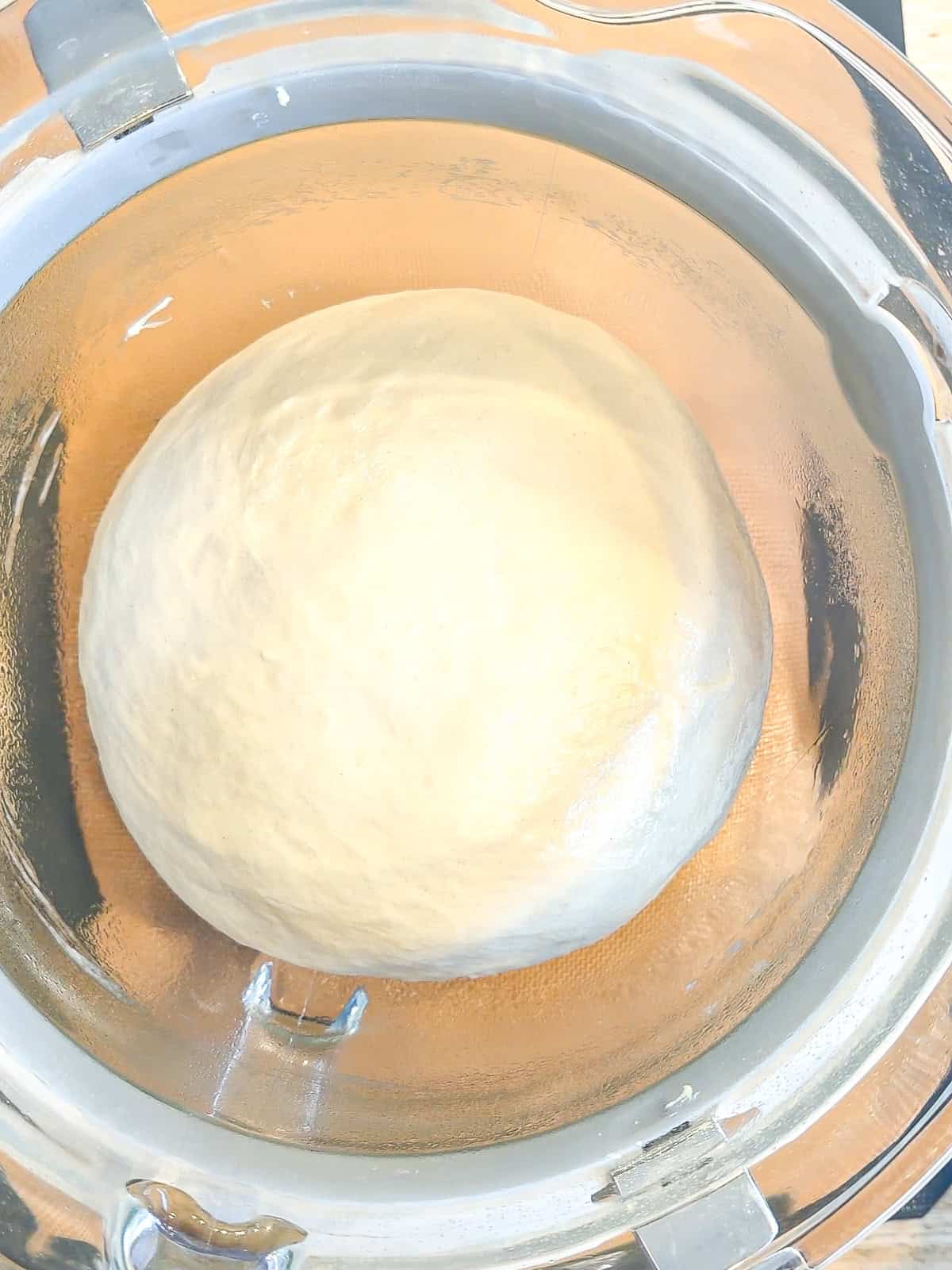 Fully risen dough in a glass bowl.