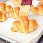 Brushing melted butter on baked crescent rolls.