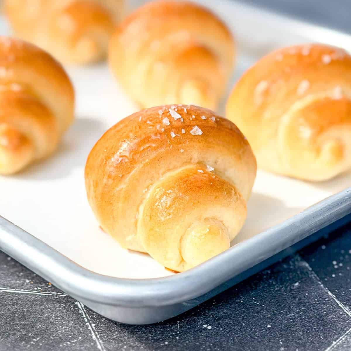 Crescent rolls on a parchment paper lined sheet pan.