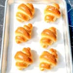 Crescent rolls on a parchment paper lined sheet pan.