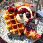 Lemon ricotta waffle with blueberries and with ricotta on a blue floral plate.