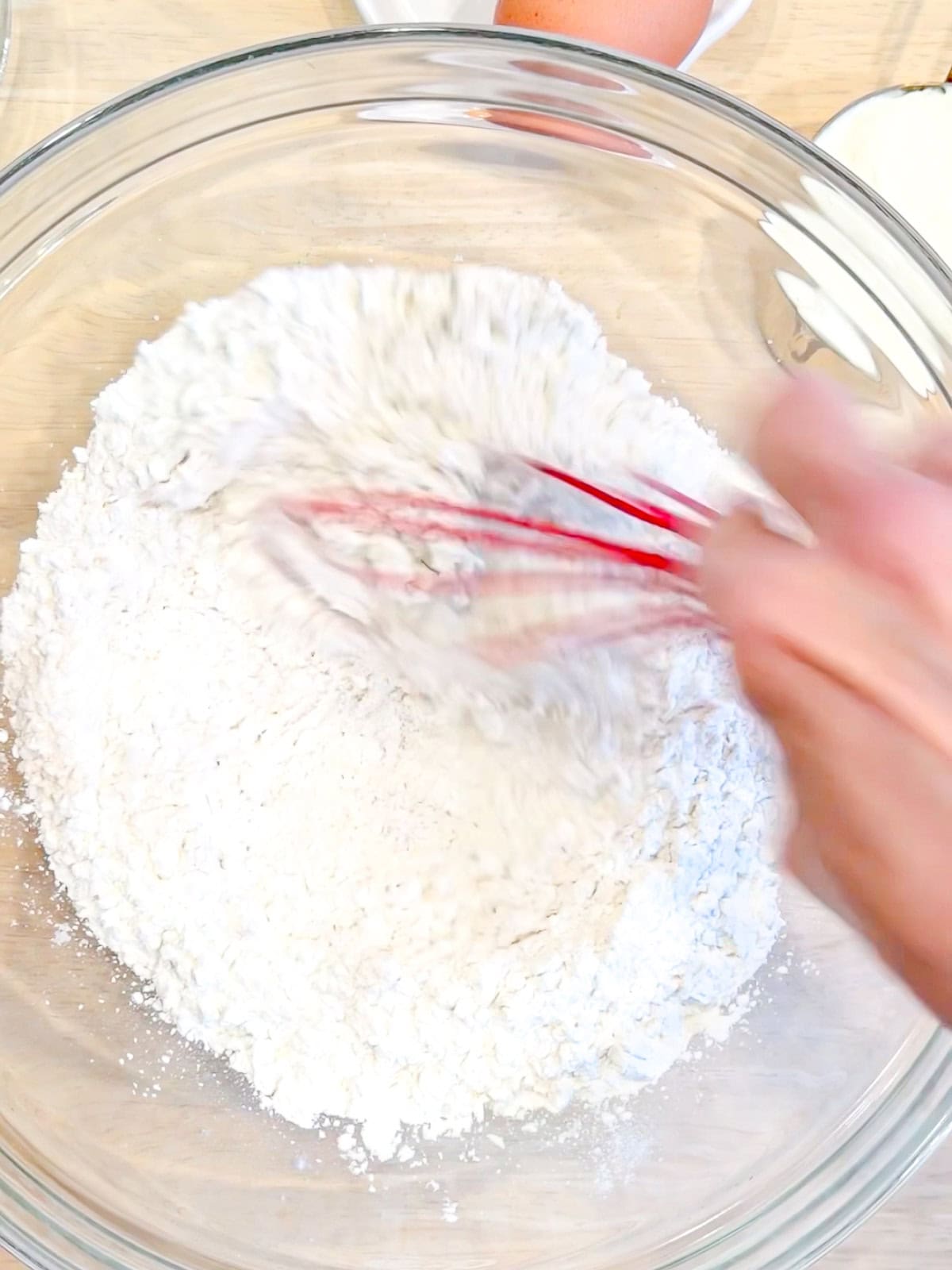 Whisking dry ingredients in a glass bowl.