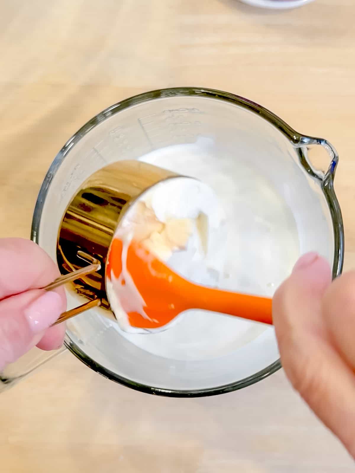 Add adding ricotta to wet ingredients in a glass pitcher.