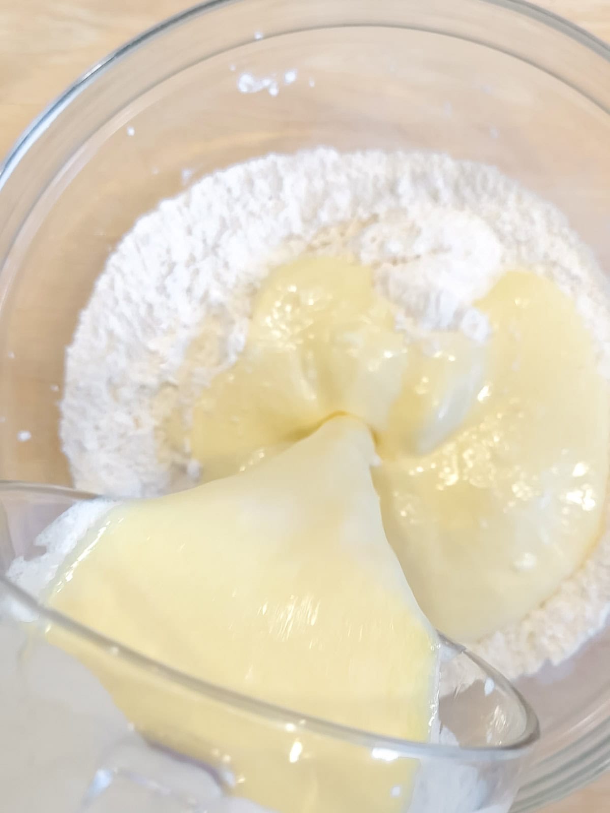 Adding wet ingredients to dry ingredients to make waffle batter.