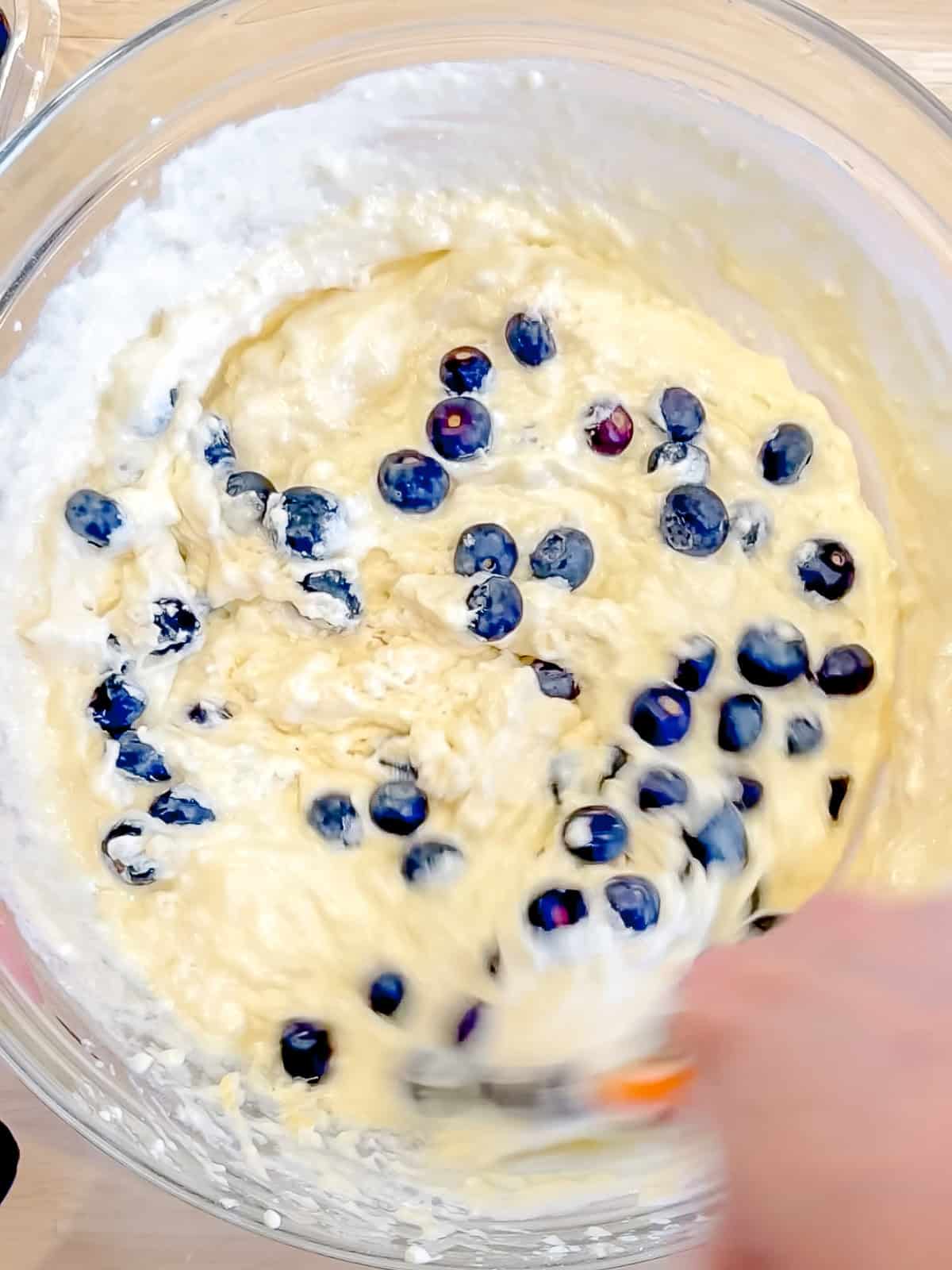 Folding blueberries into waffle batter.