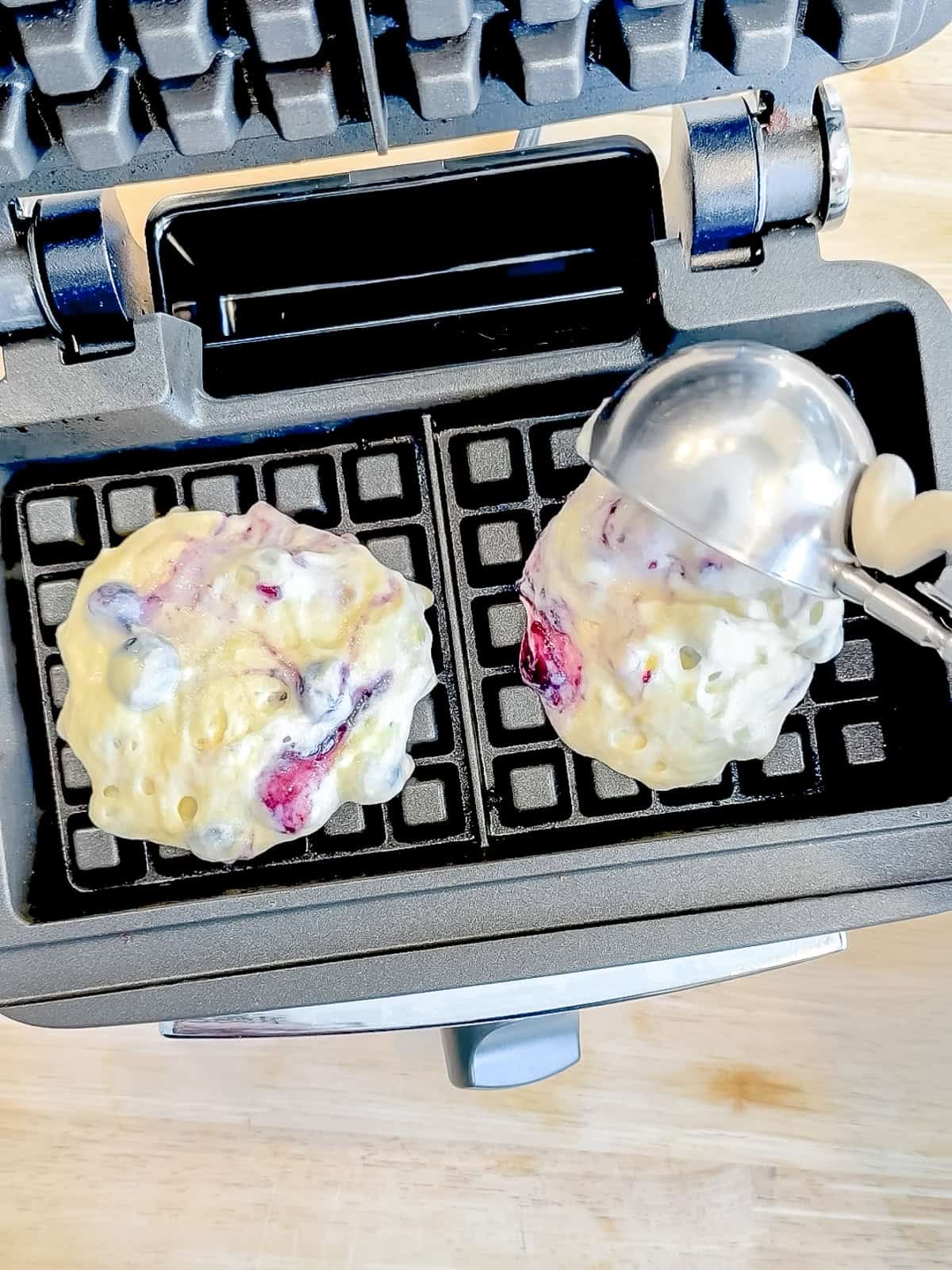 Scooping waffle batter into a waffle maker.