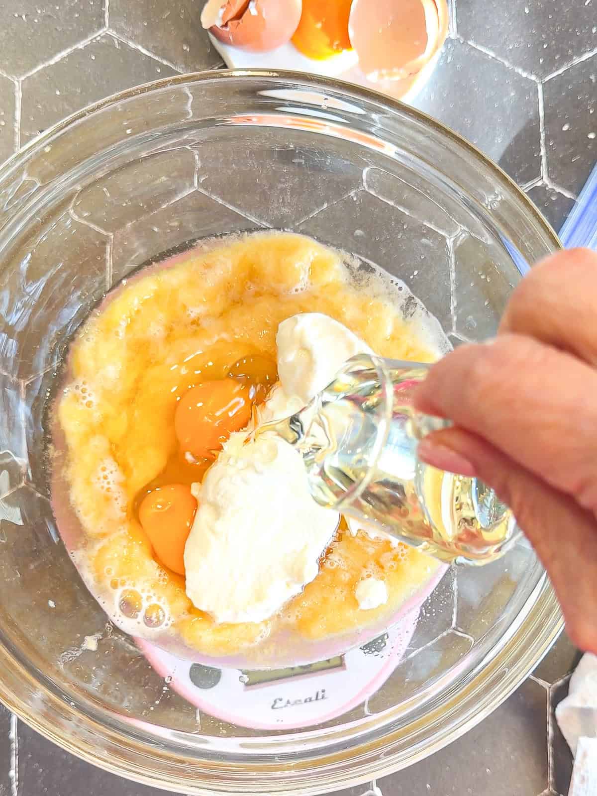 Adding vegetable oil to other wet ingredients in a glass bowl.