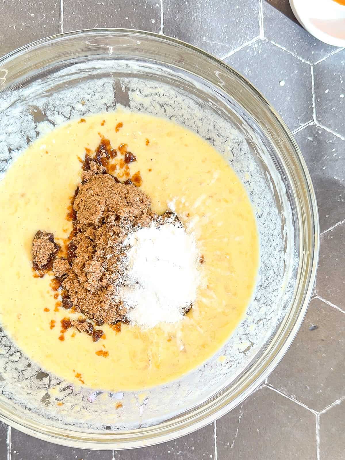 Wet ingredients with brown sugar and baking powder in a glass bowl.